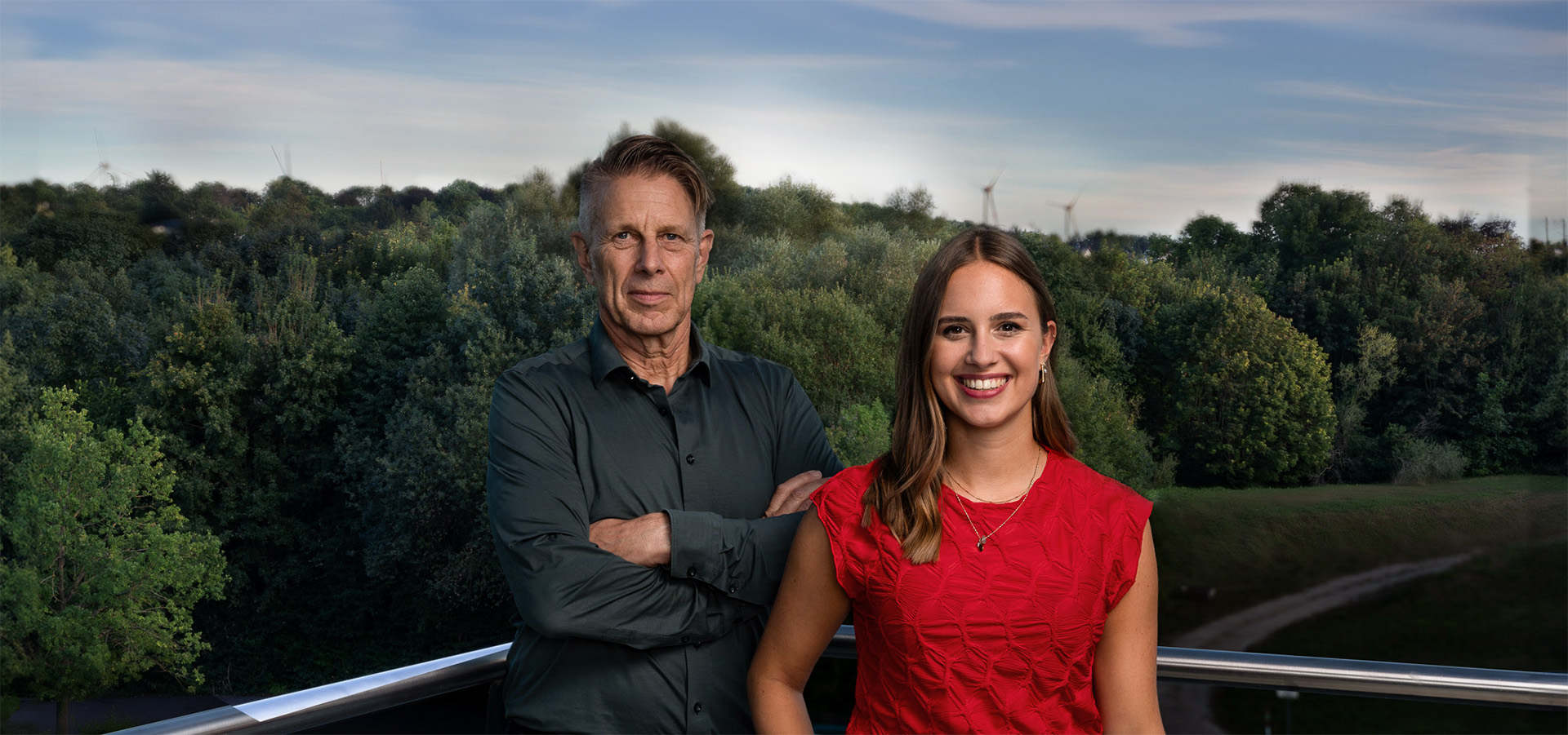 Jochen und Milena Greim posieren auf einer Terrasse mit Blick auf Wald und Windräder – Symbol für Nachhaltigkeit und die langfristigen Partnerschaften, die das Unternehmen prägt.