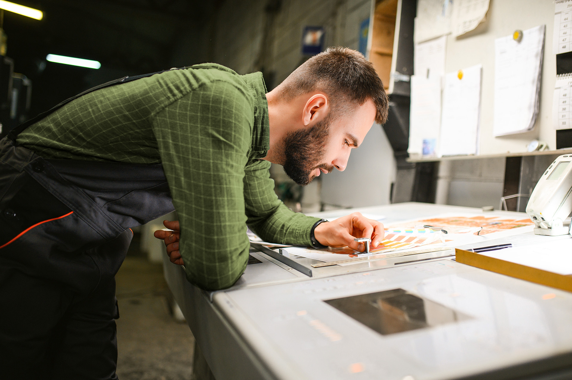 Ein Mann inspiziert Materialien an einer Maschine, was die operative Umsetzung der familiengeführten Unternehmensgruppe in Bereichen wie Logistik oder Fulfillment zeigt.