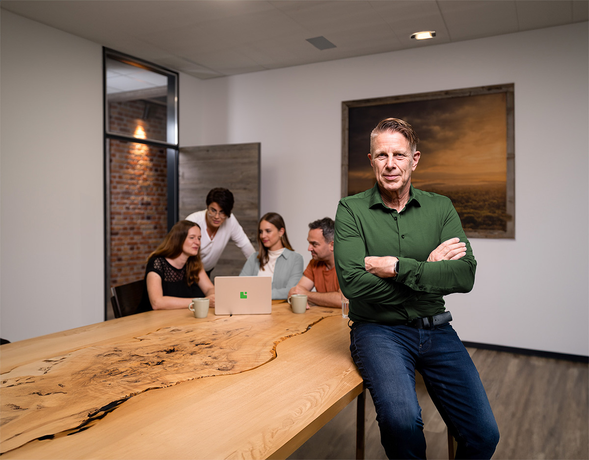 Ein Team der Greim Gruppe im modernen Meetingraum: Fünf Mitarbeiter arbeiten an einem Holztisch zusammen, repräsentativ für die familiengeführte Unternehmensgruppe, die Unternehmen mit praxisnahen Logistik- und Dienstleistungslösungen begleitet.